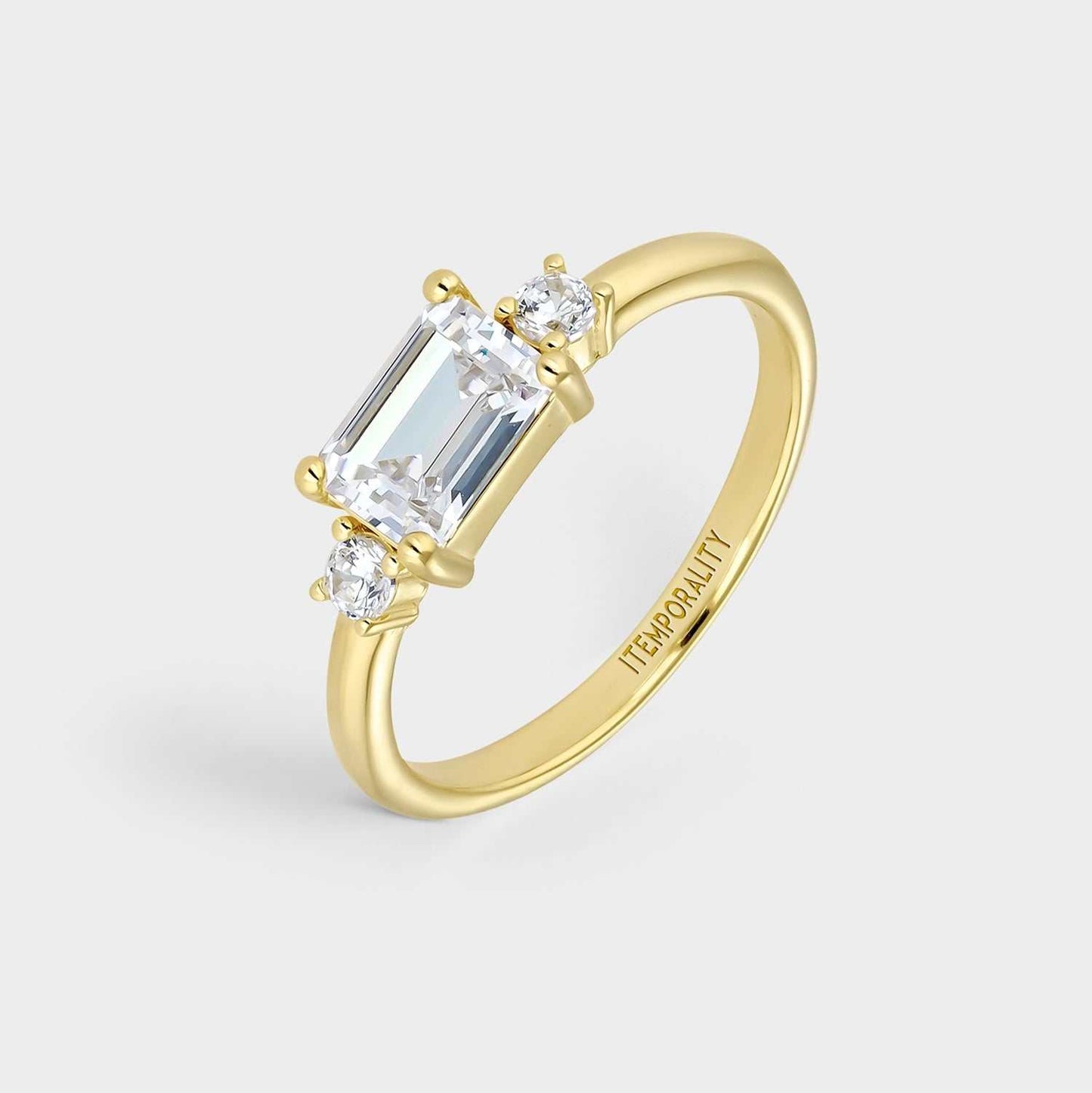 Anillo  de plata bañada en oro amarillo con circonita central blanca rectangular engastada en cuatro garras y dos circonitasa  redondas blancas a ambos lados