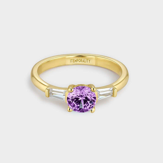 Gelbvergoldeter Silberring mit zwei rechteckigen weißen Zirkonen und einem größeren runden zentralen amethystfarbenen Zirkon.