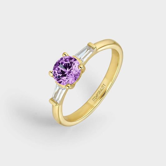 Anillo  de plata bañada en oro amarillo con dos circonitas blancas rectangulares y circonita central redonda de mayor tamaño color amatista.