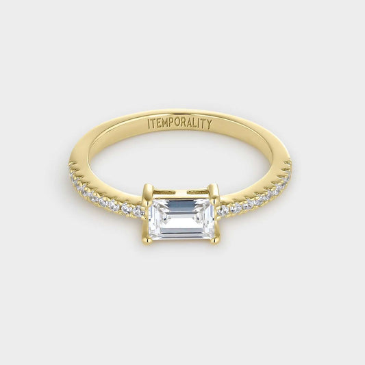 Anillo de plata bañada en oro amarillo con circonita blanca rectangular engastada en cuatro garras y circonitas pequeñas blancas en la mitad de la circunferencia