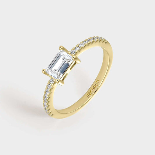 Anillo  de plata bañada en oro amarillo con circonita blanca rectangular engastada en cuatro garras y circonitas pequeñas blancas en la mitad de la circunferencia