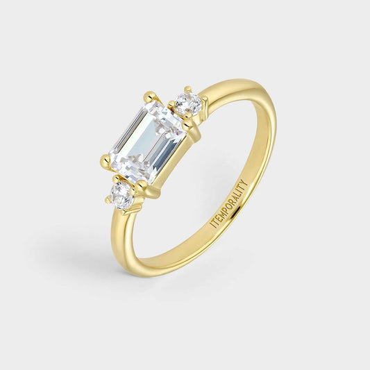 Anillo  de plata bañada en oro amarillo con circonita central blanca rectangular engastada en cuatro garras y dos circonitasa  redondas blancas a ambos lados